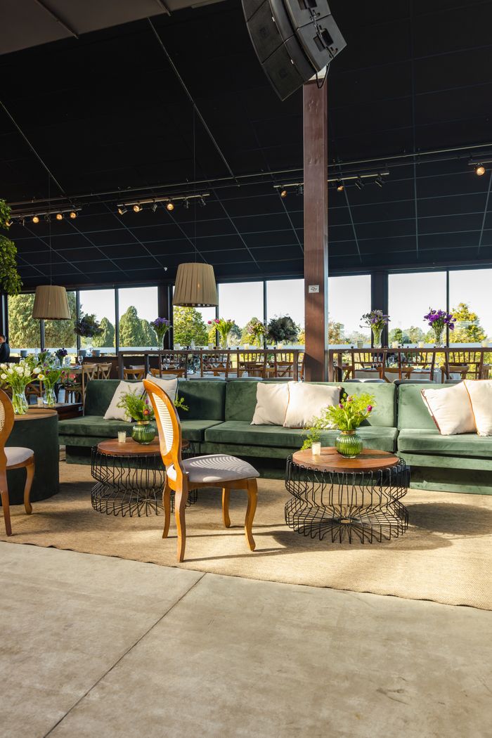 Stylish banquet hall with green sofas, decorative plants, and inviting ambiance for events.